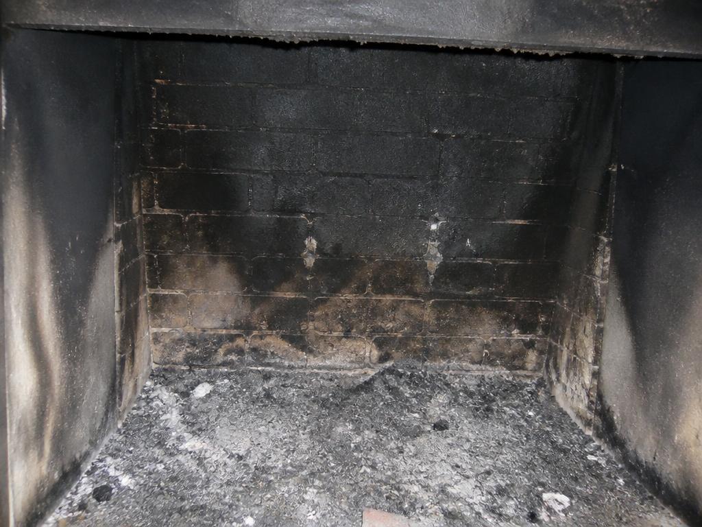 Fireplace firebox with heavy soot and creosote buildup before cleaning